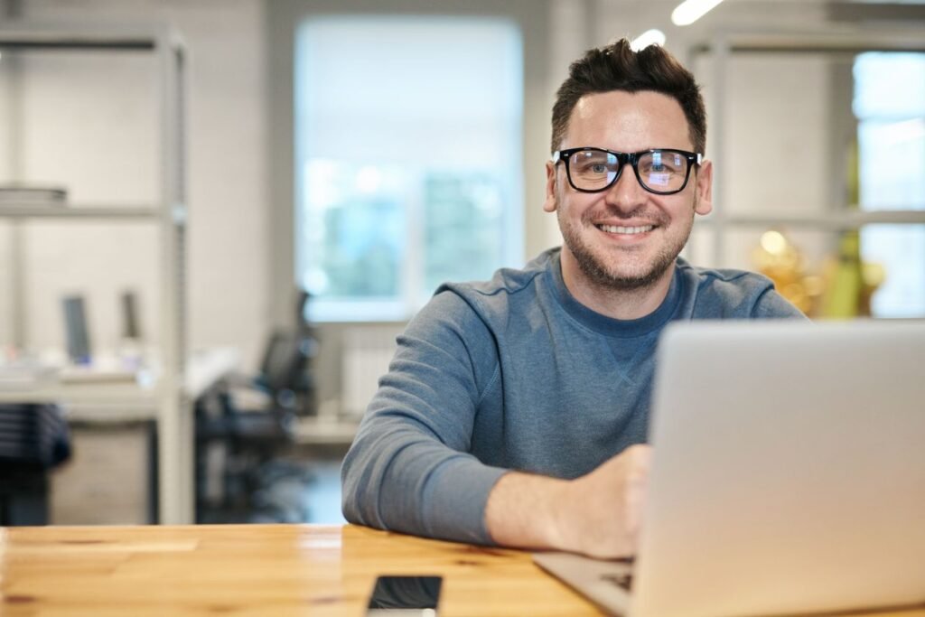 Smiling man working on a laptop in a bright modern office
