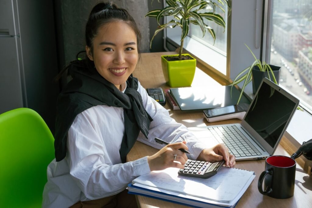 Smiling woman using a calculator in a bright office